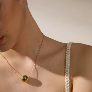 Close-up of a person wearing a delicate gold necklace with a small pendant.