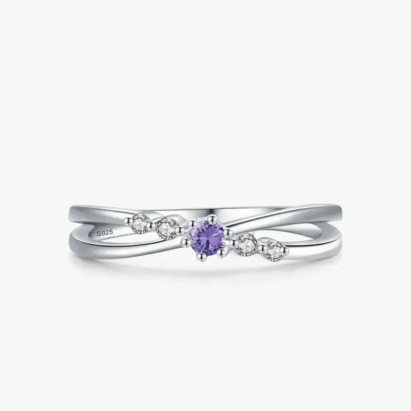 Sterling silver ring with twisted band, purple gemstone center, and small clear accent stones.