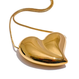Gold heart-shaped clutch with a chain on a white background