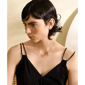 Woman wearing a black dress and a delicate gold-plated heart pendant necklace