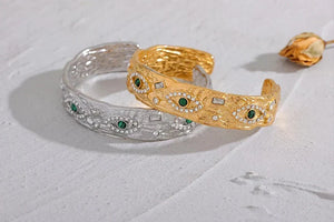 Gold and silver bangles with green gemstones on a light gray background, featuring the Vogue logo.