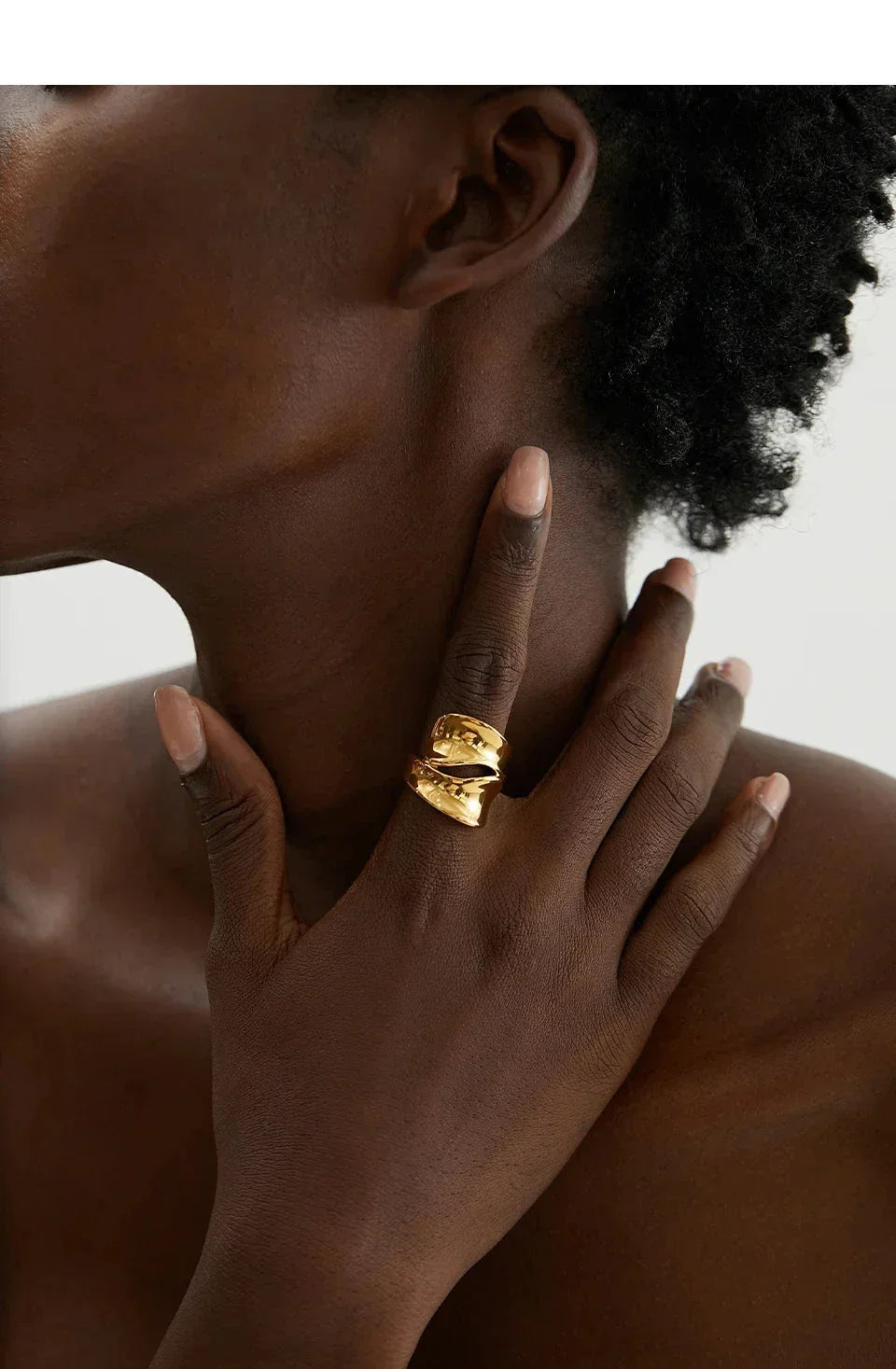Woman wearing a bold, wide 18K gold-plated statement ring on her finger