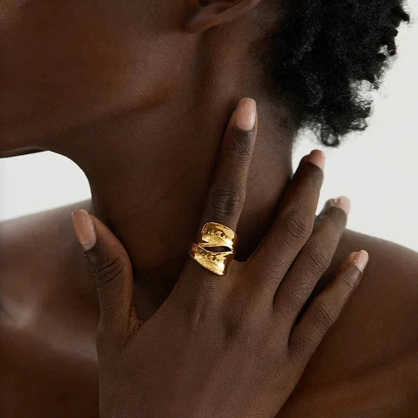 Woman wearing a bold, wide 18K gold-plated statement ring on her finger