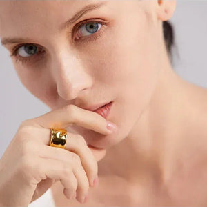 Woman wearing a bold, wide 18K gold-plated ring on her finger, close-up view