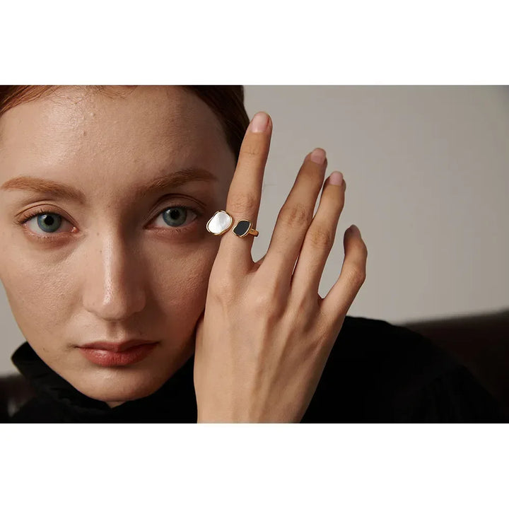 Woman wearing a gold-plated open ring with black and white stones, elegant jewelry