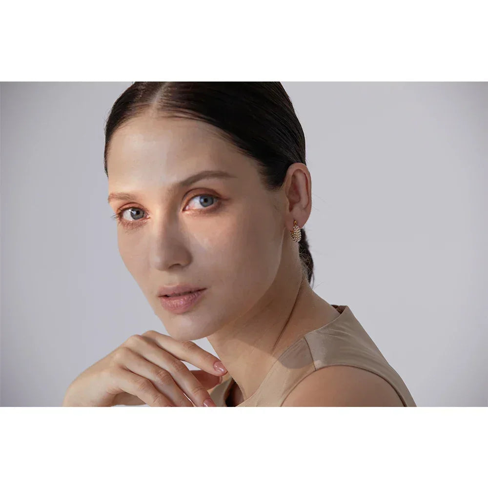 Woman wearing gold-plated, textured stud earrings, elegant jewelry close-up portrait