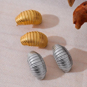 Decorative shells in gold and silver on a textured surface with natural elements.