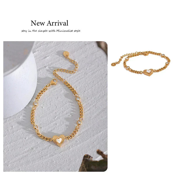 Gold bracelet with heart-shaped charm on a textured white surface