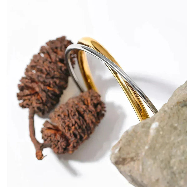 Gold and silver bracelet on a stone background with 'NEW++' branding.
