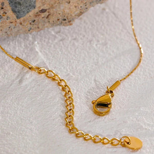 Gold necklace with clasp on a textured surface