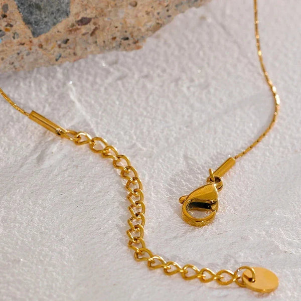 Gold necklace with clasp on a textured surface