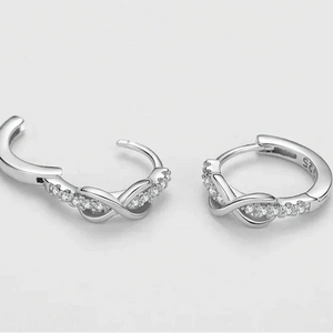 Silver hoop earrings with small diamonds on a light gray background
