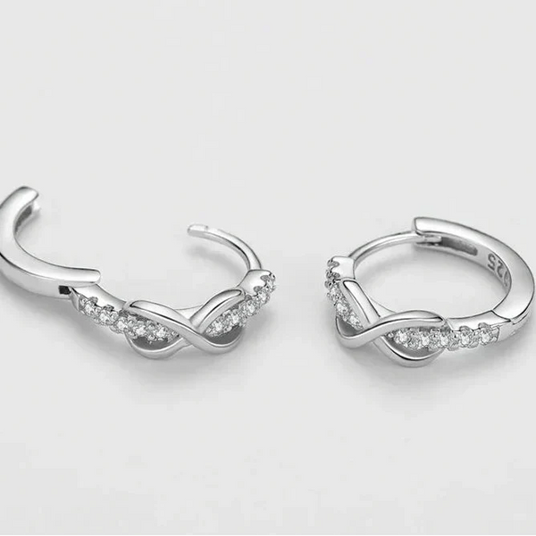 Silver hoop earrings with small diamonds on a light gray background