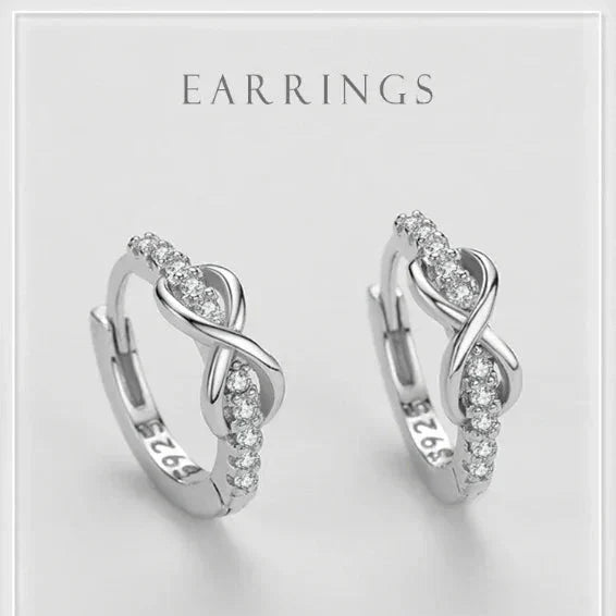 Pair of silver earrings with clear stones on a light gray background