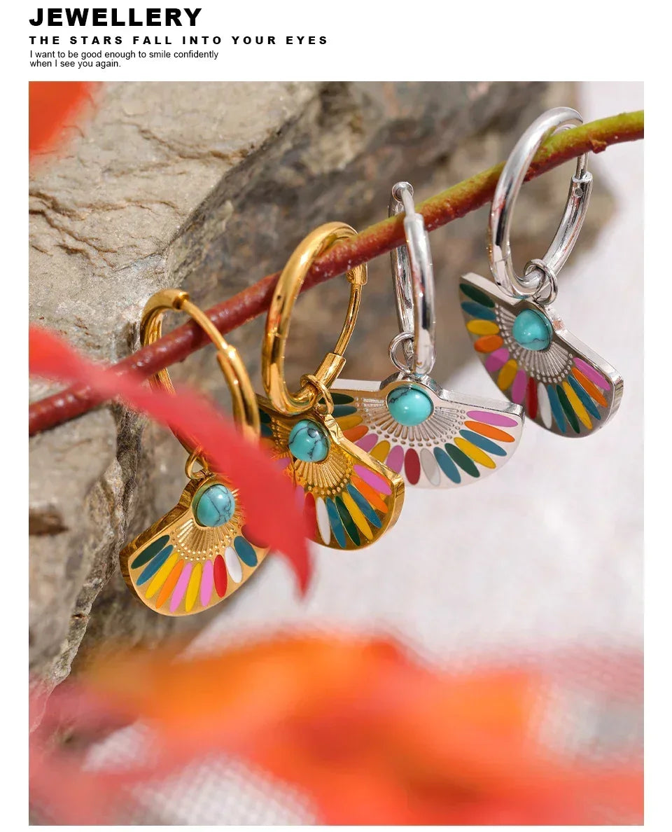 Colorful fan-shaped hoop earrings in gold and silver with turquoise stones on a branch