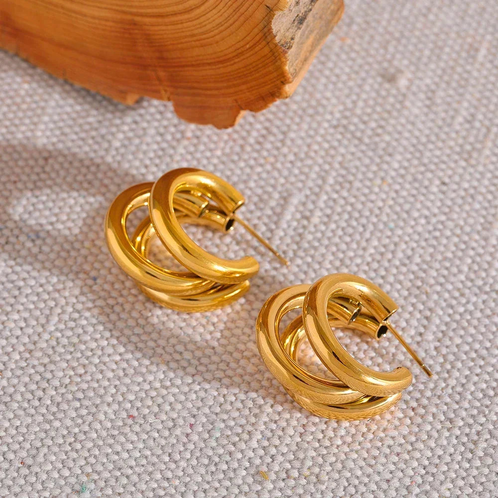 Chunky 18K gold-plated hoop earrings on textured fabric background, elegant jewelry