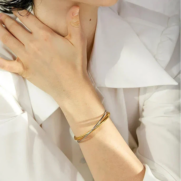 Woman wearing minimalist 18K gold-plated and silver bangle bracelet, white blouse