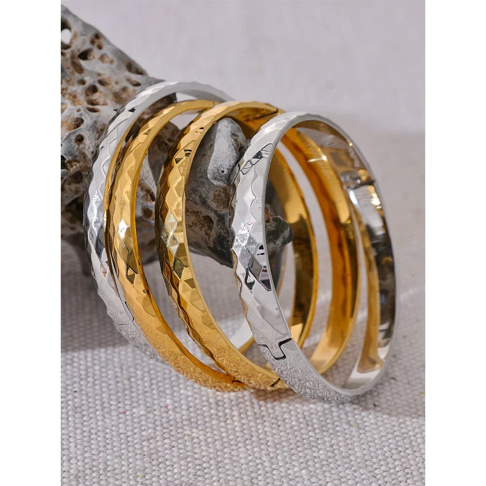 Stacked hammered 925 silver and gold-plated bangles on textured stone, elegant jewelry
