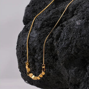 Gold necklace draped over a textured black surface