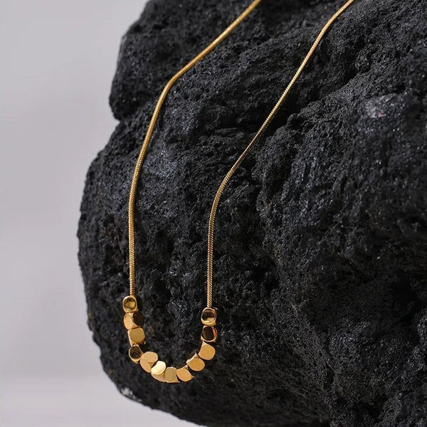 Gold necklace draped over a textured black surface