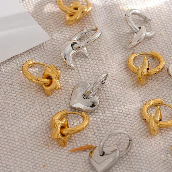 Gold and silver earrings on a textured surface with 'Happy Everyday' branding.