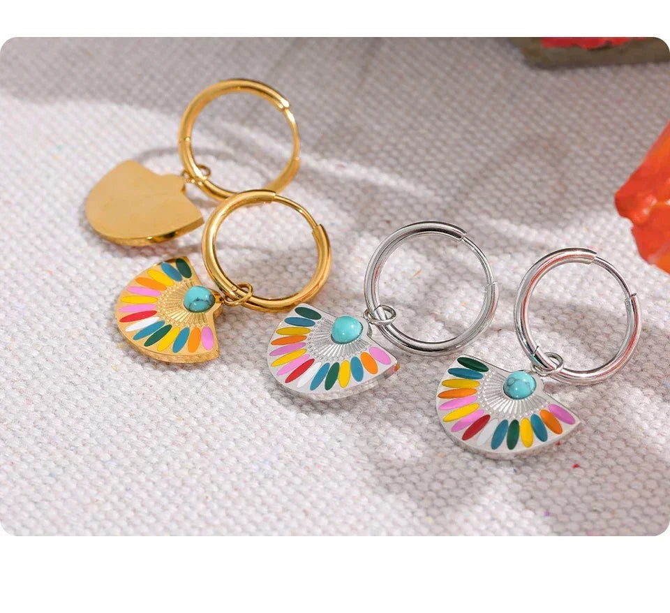 Colorful fan-shaped enamel dangle earrings in gold and silver tones with turquoise accents on fabric