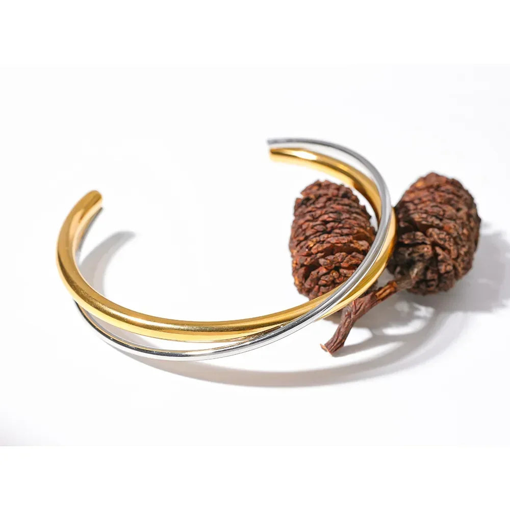 Dual-tone 18K gold-plated and silver cuff bracelet displayed with pine cones on white background