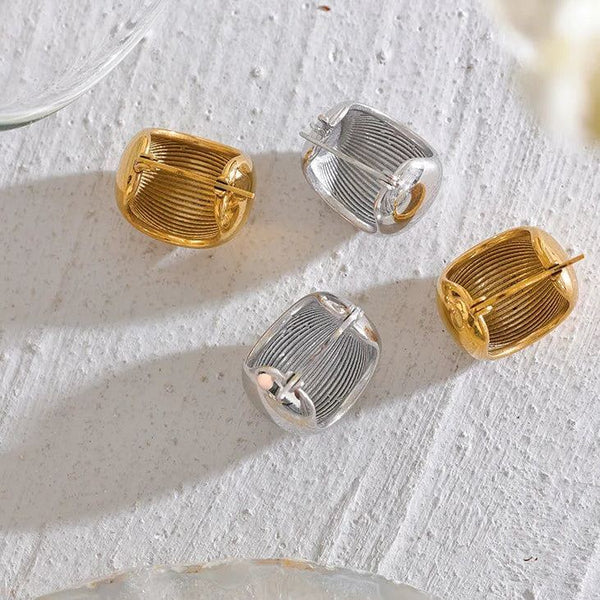 Gold and silver geometric earrings on a textured white surface