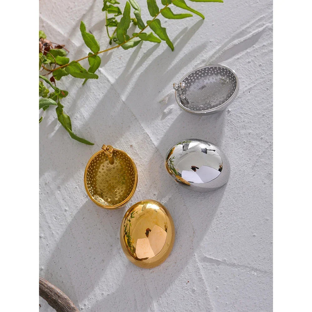 Gold and silver oval locket pendants with textured and polished finishes on a white surface
