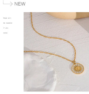 Gold necklace with a circular pendant on a white fabric background