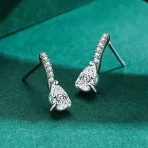 Silver teardrop earrings with clear stones on a green fabric background