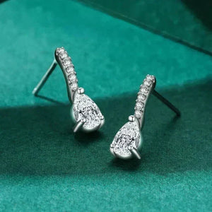 Silver teardrop earrings with clear stones on a green fabric background
