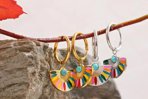 Colorful fan-shaped enamel drop earrings in gold and silver, displayed on a branch.