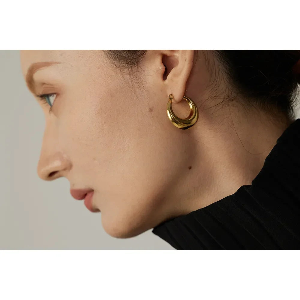 Woman wearing chunky gold-plated hoop earring, side profile, elegant minimalist jewelry