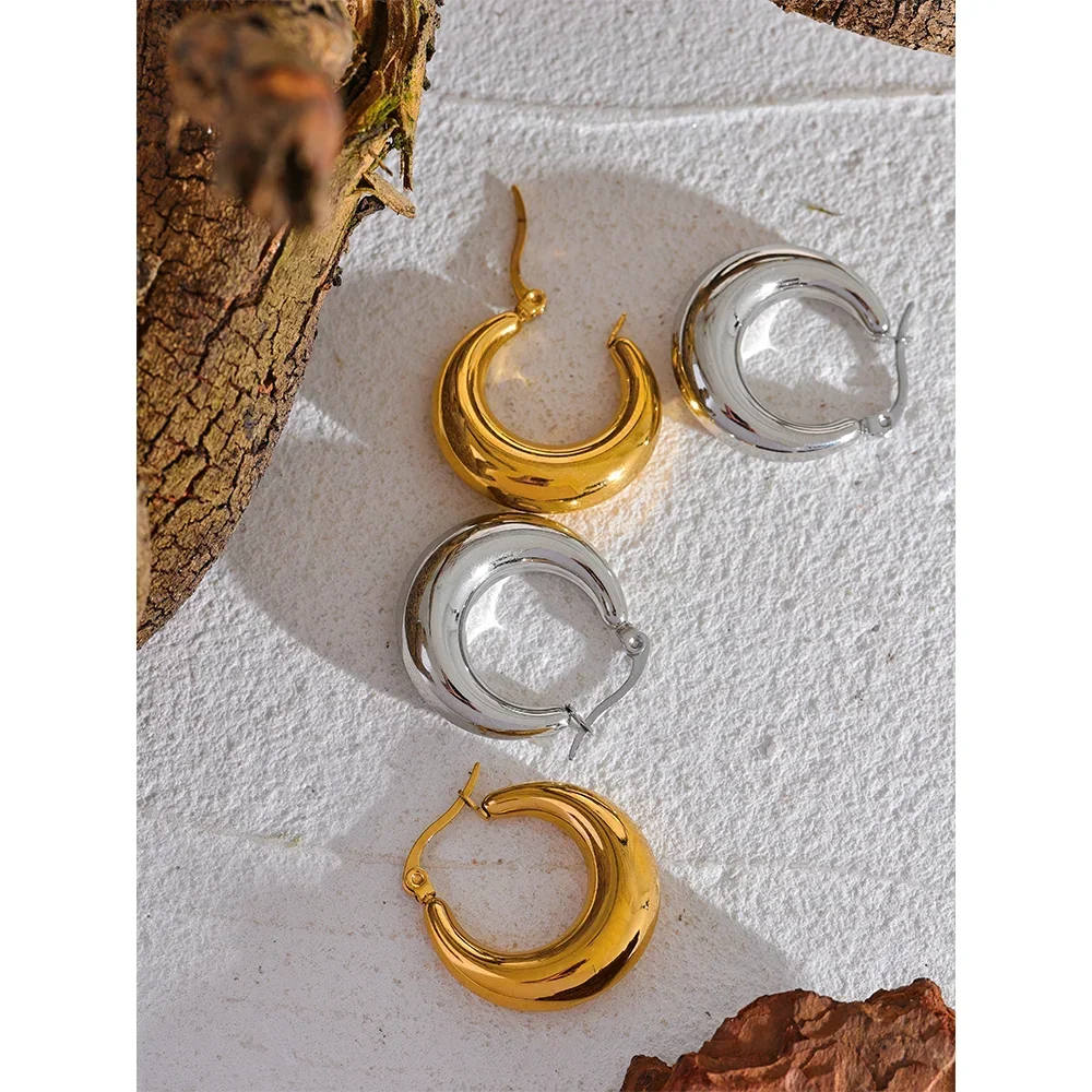 Gold and silver chunky hoop earrings on textured white background with bark accents