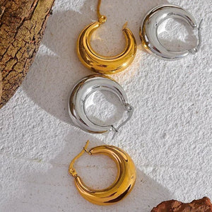 Gold and silver chunky hoop earrings on textured white background with bark accents