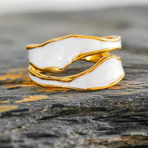 18K gold-plated white enamel wavy ring on textured stone surface