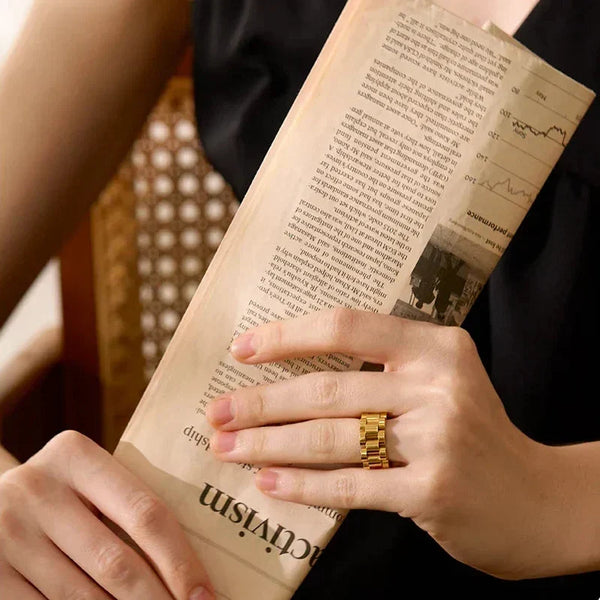 Woman wearing a chunky gold-plated statement ring and black sleeveless top