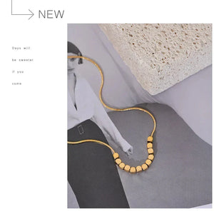 Gold necklace on a gray surface with a minimalistic background