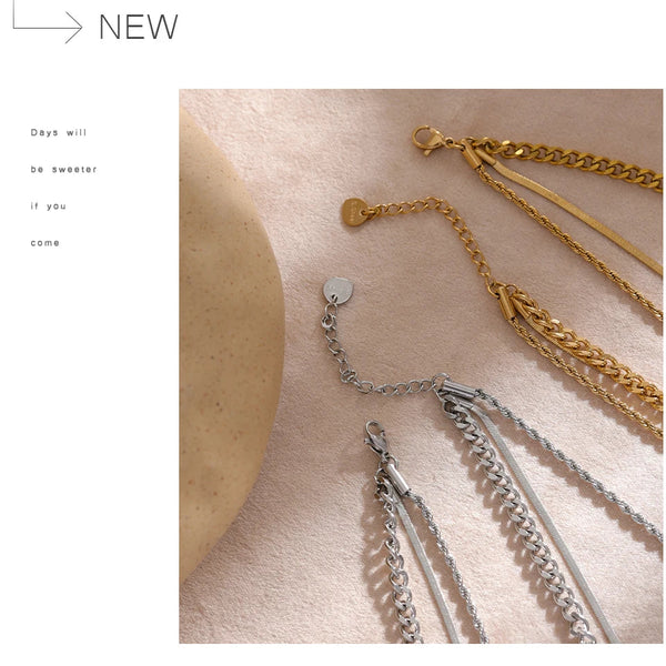 Three gold and silver chain necklaces on a person's skin with a minimal background.