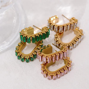 Gold hoop earrings with green and pink gemstones on a white background