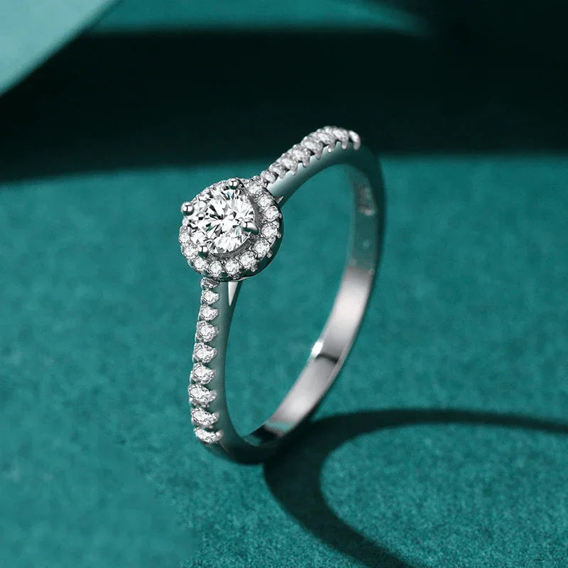 925 silver ring with round halo setting and pavé cubic zirconia on a teal background