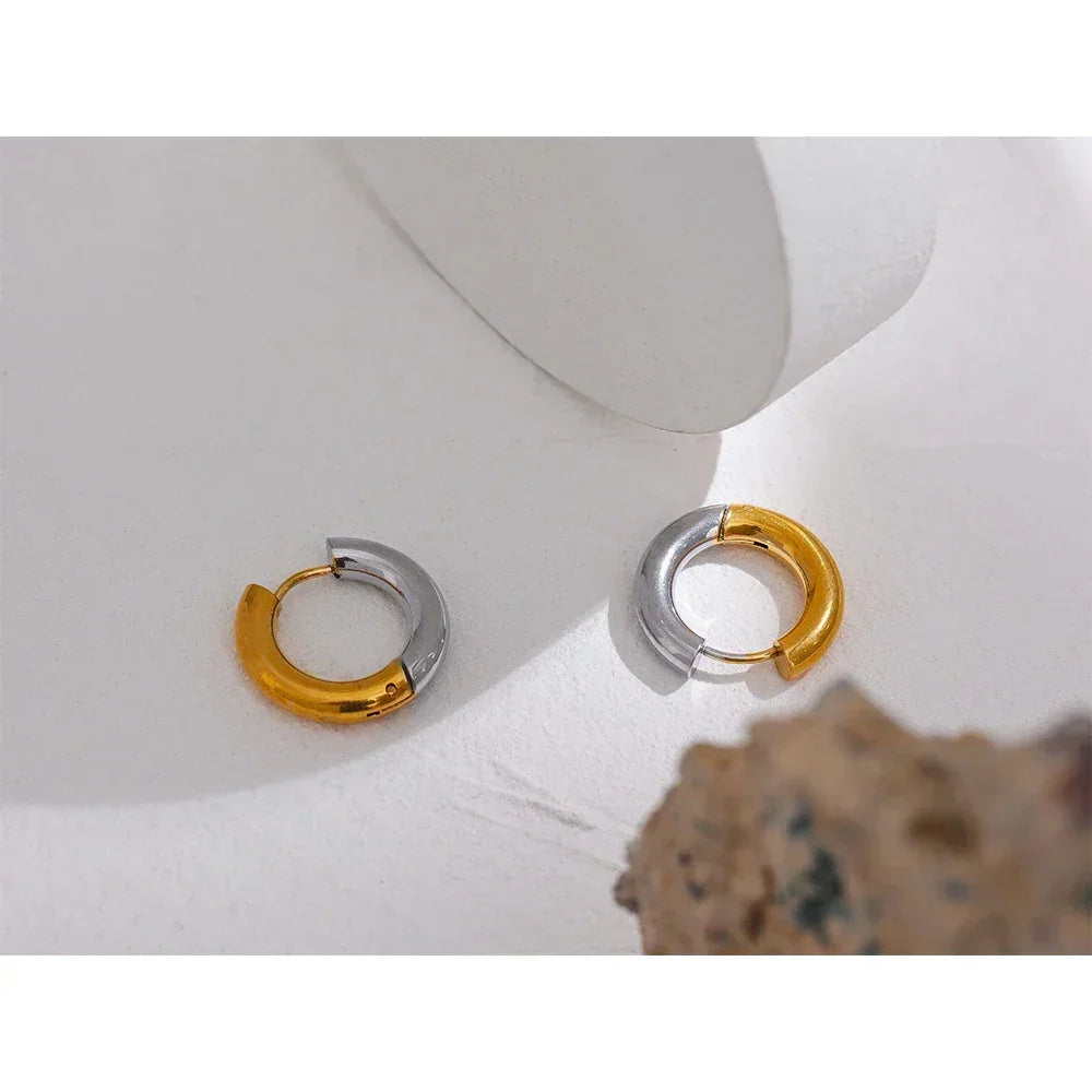 Pair of two-tone gold and silver chunky hoop earrings on a white surface
