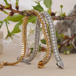 Three gold and silver bracelets on a branch with flowers in the background