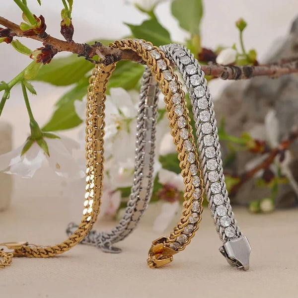 Three gold and silver bracelets on a branch with flowers in the background