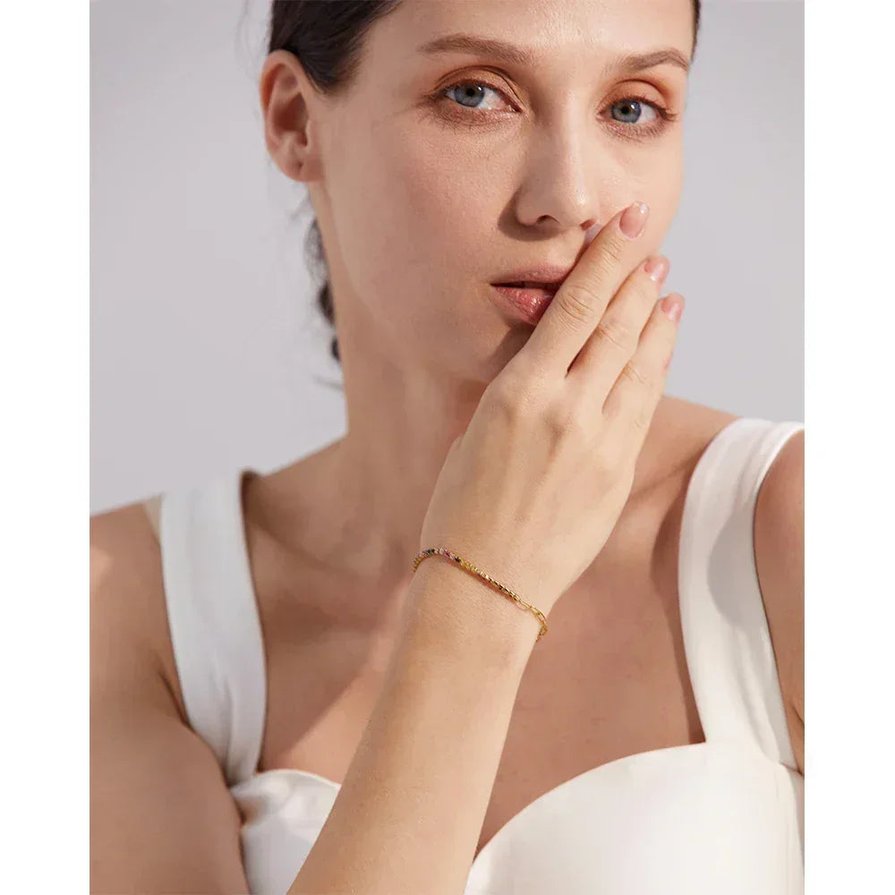 Woman wearing delicate 18K gold-plated bracelet in elegant white dress