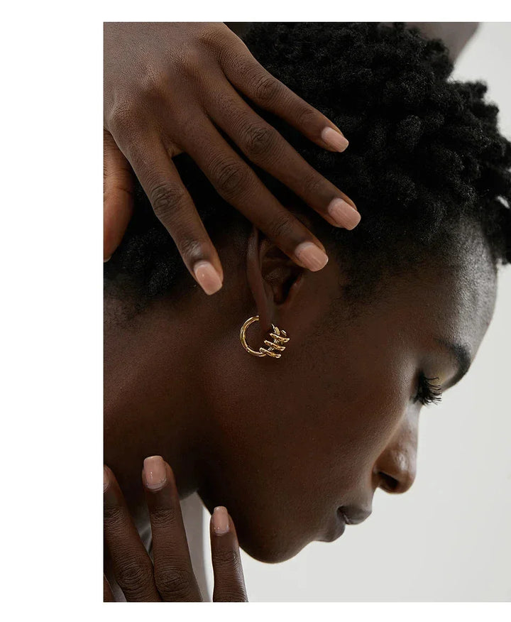 Woman wearing gold-plated hoop earring, close-up jewelry detail