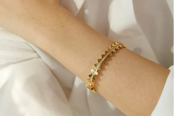 Gold bracelet on a wrist with a white background