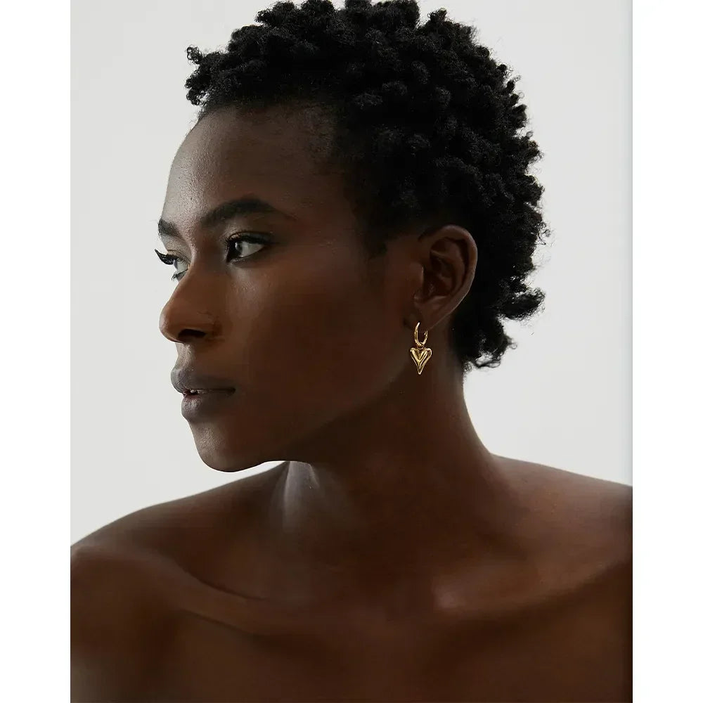 Woman wearing a gold-plated heart-shaped earring, elegant minimalist jewelry