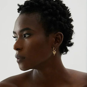 Woman wearing a gold-plated heart-shaped earring, elegant minimalist jewelry